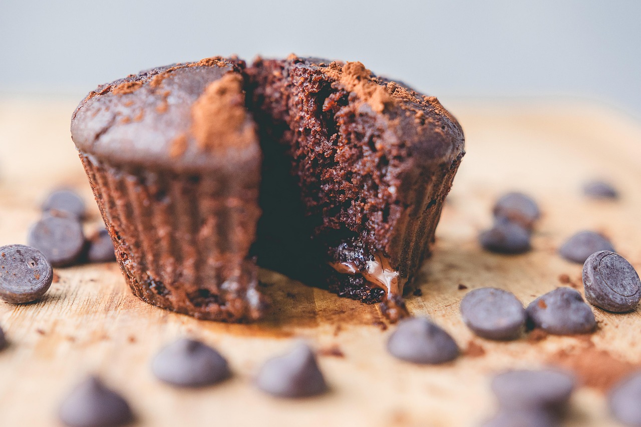 A chocolate muffin broken open on a wooden board